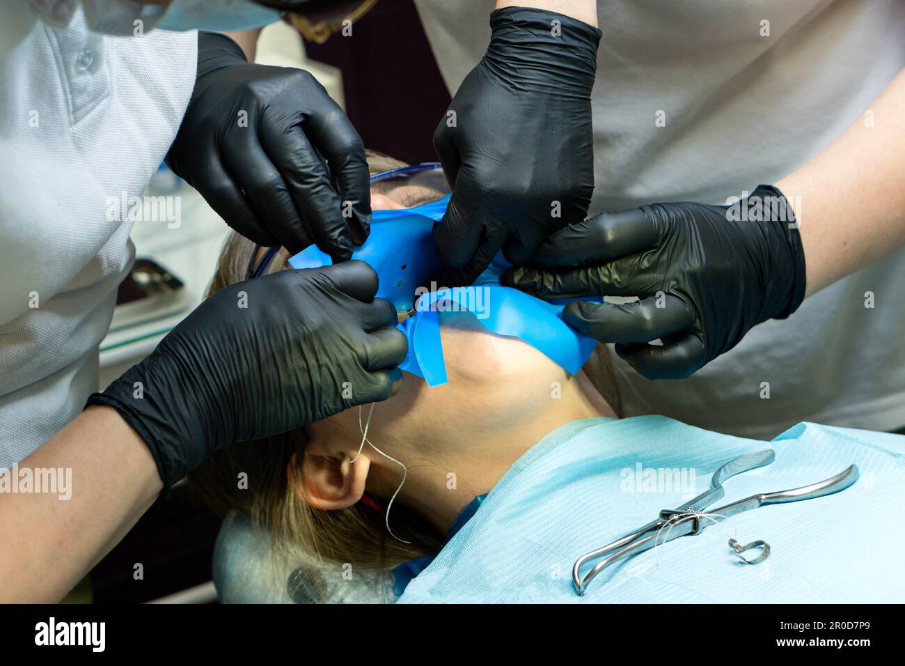 Doctor and help assistant isolate patient's teeth with rubber pad