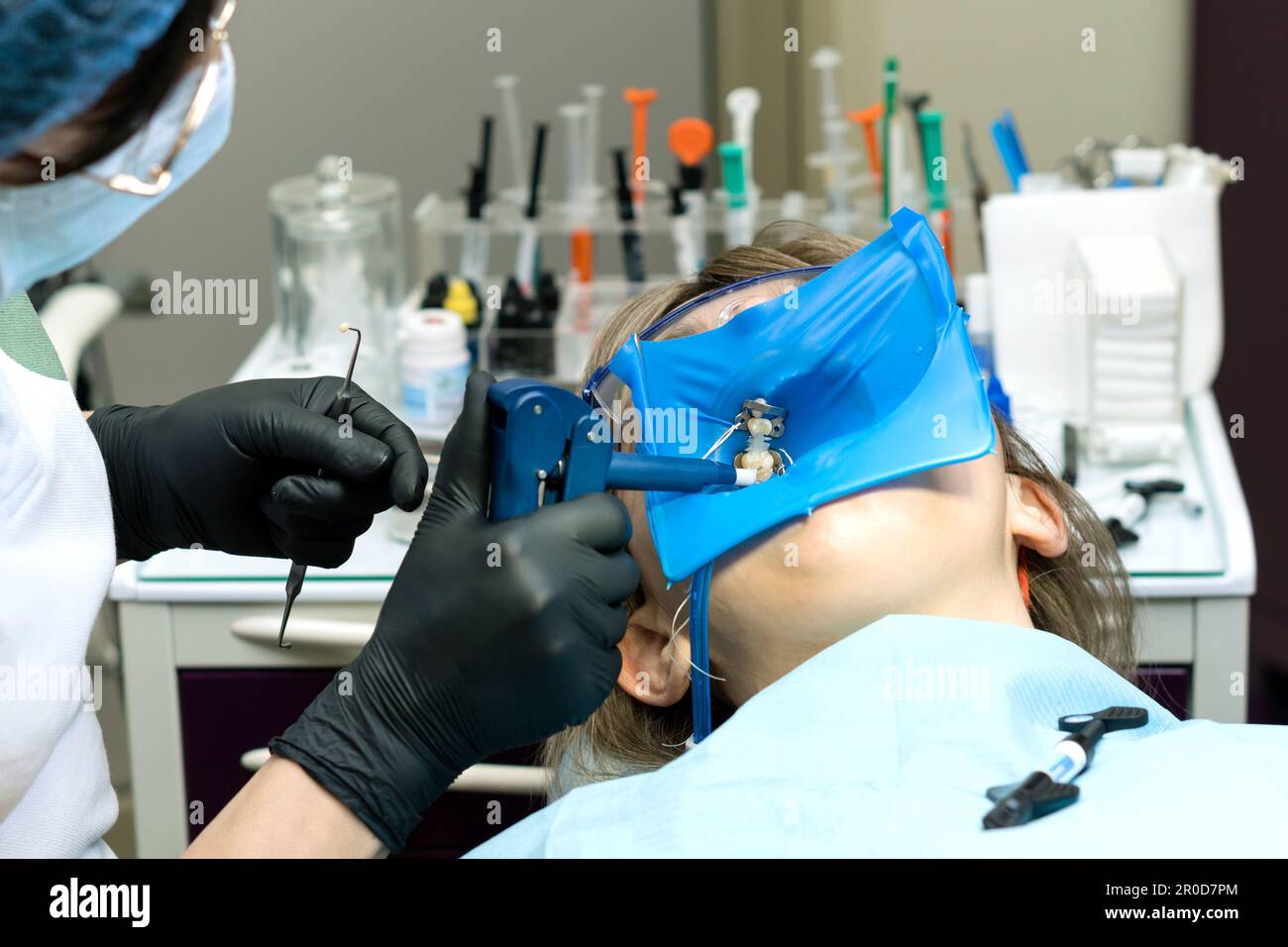Doctor dentist using of rubber dam system with latex scarves and metal