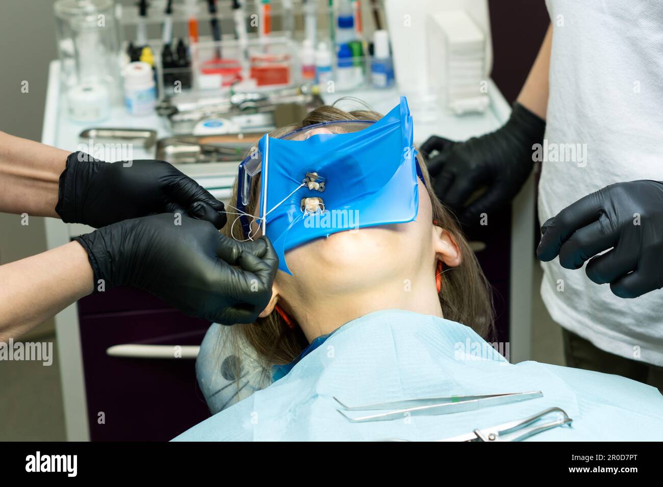 Doctor and help assistant isolate patient's teeth with rubber pad