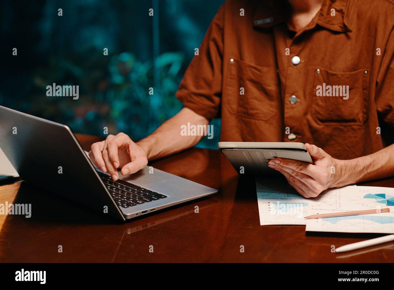 Businessman comparing figures on tablet computer and on laptop screen Stock Photo