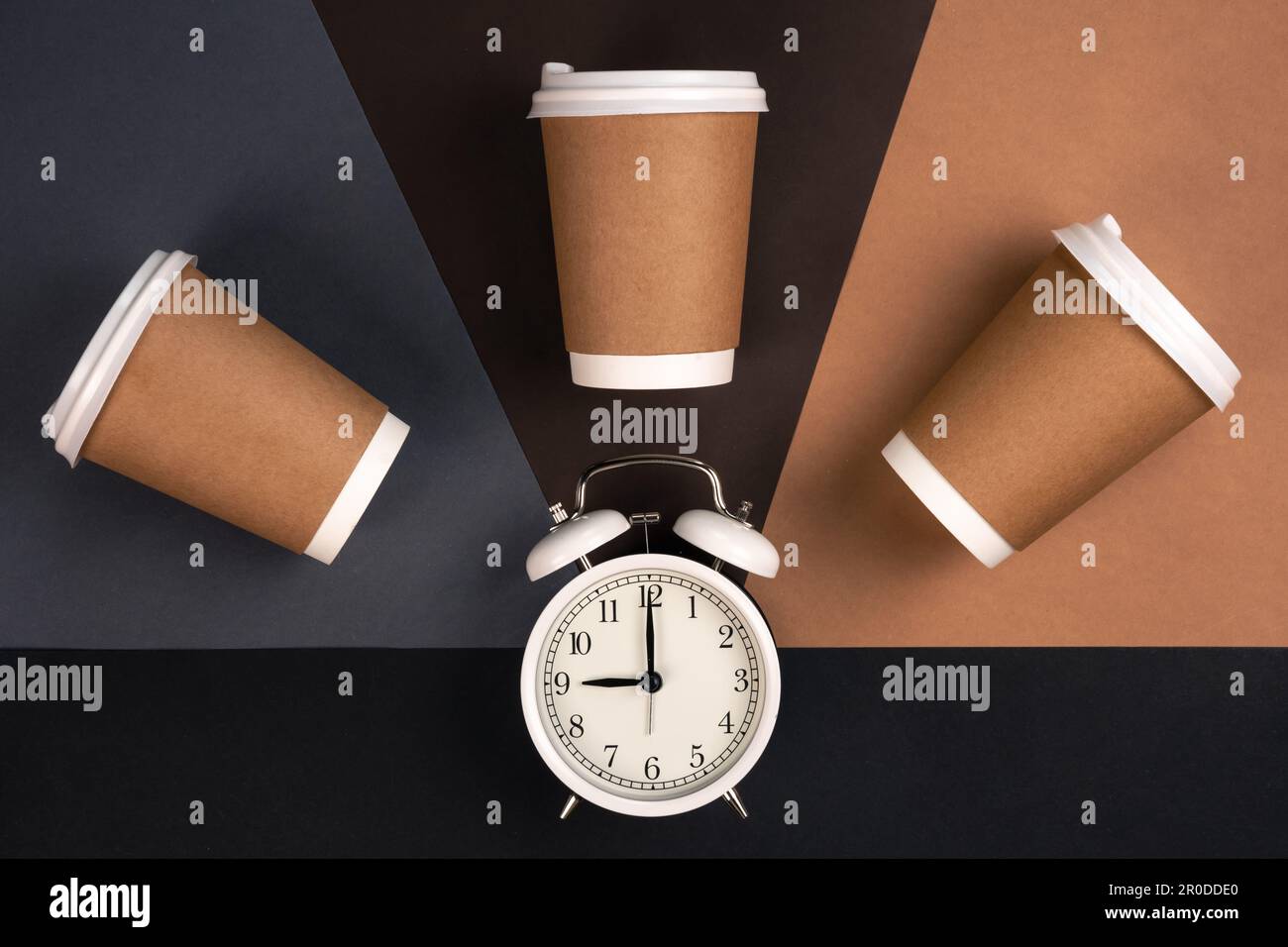 Disposable paper cups and white alarm clock on paper background, top ...