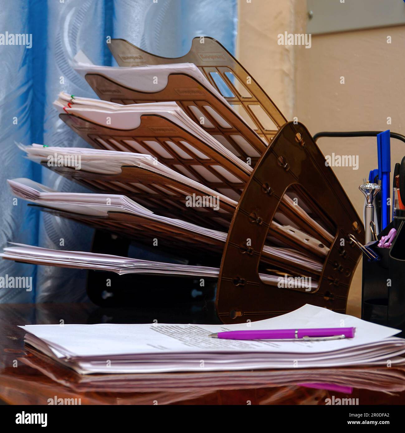 Plastic organizer for documents on the office desk. The pink pen lies on business papers, documents Stock Photo