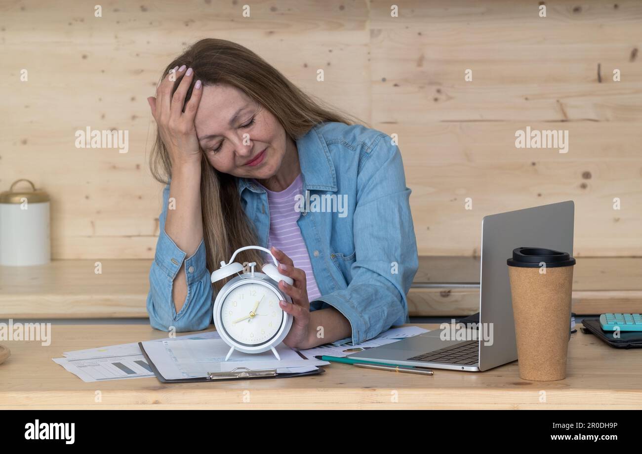 A thoughtful woman drinking a lot of coffee while doing creative work Stock Photo