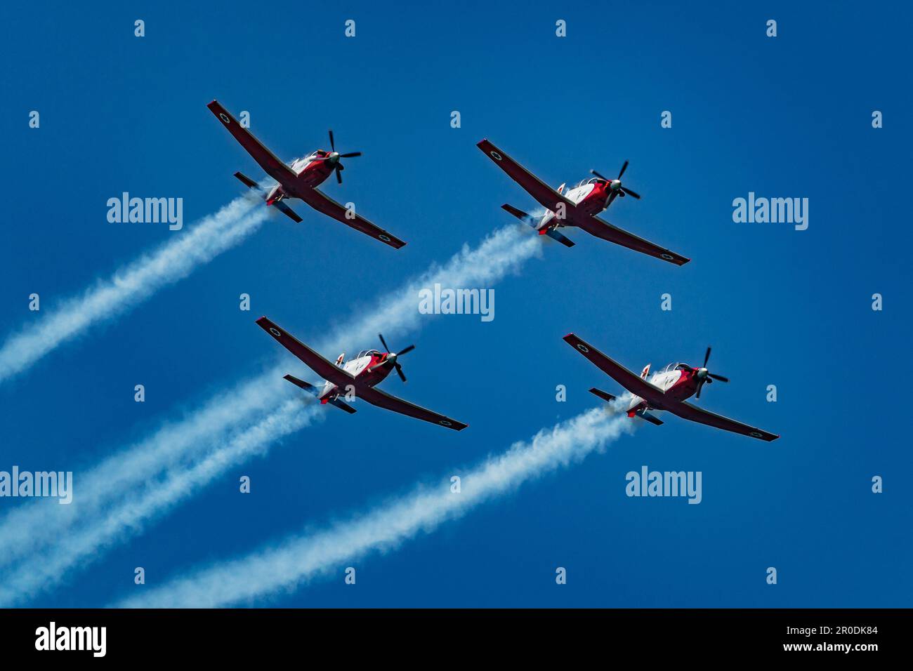 Four planes flying in formation with one leading the way, leaving a