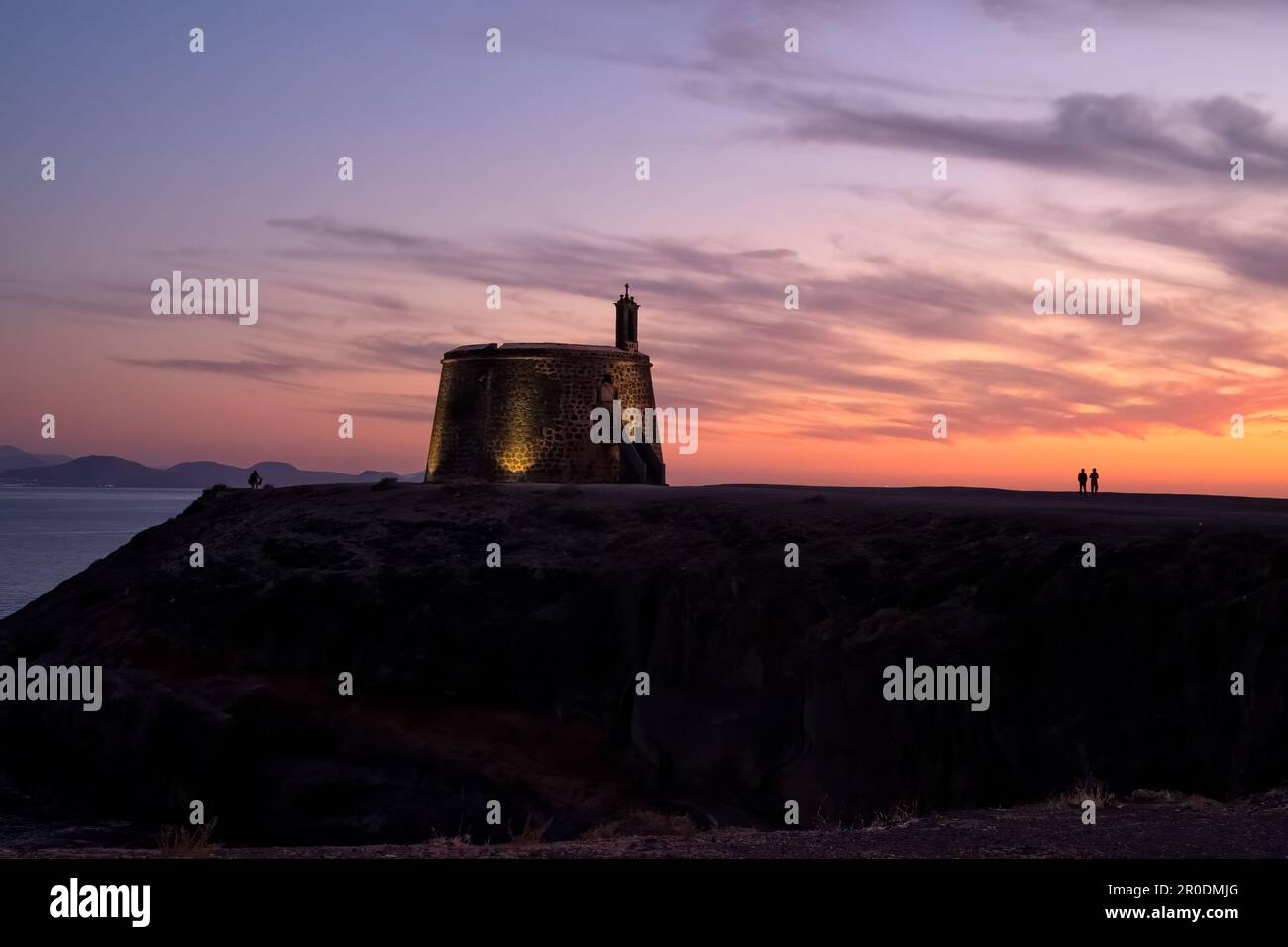 An illuminated Castillo de las Coloradas or Torre del Águila near Playa Blanca, Lanzarote in the Canary Islands silhouetted against a beautiful sunset Stock Photo