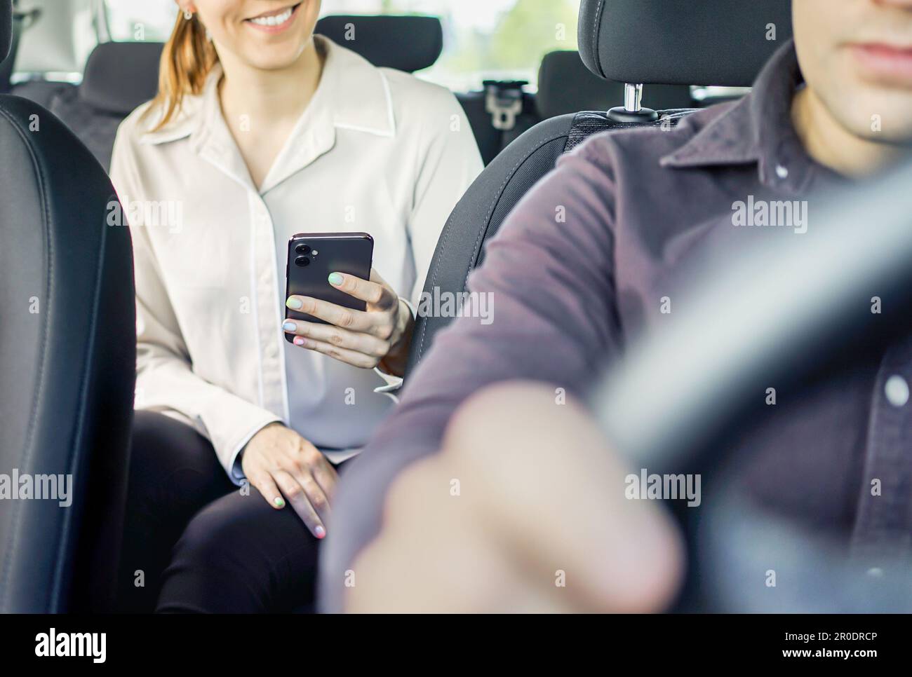 Taxi or rideshare car passenger using phone to pay for cab ride. Mobile payment, tip or review. Happy customer and driver. Woman holding cellphone. Stock Photo