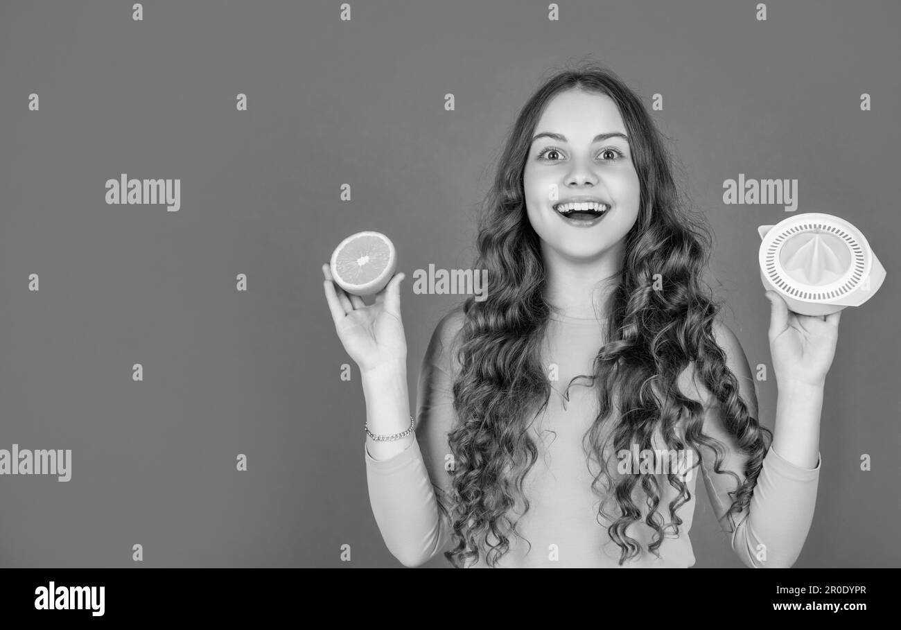 happy teen girl hold orange and juicer on pink background with copy space Stock Photo