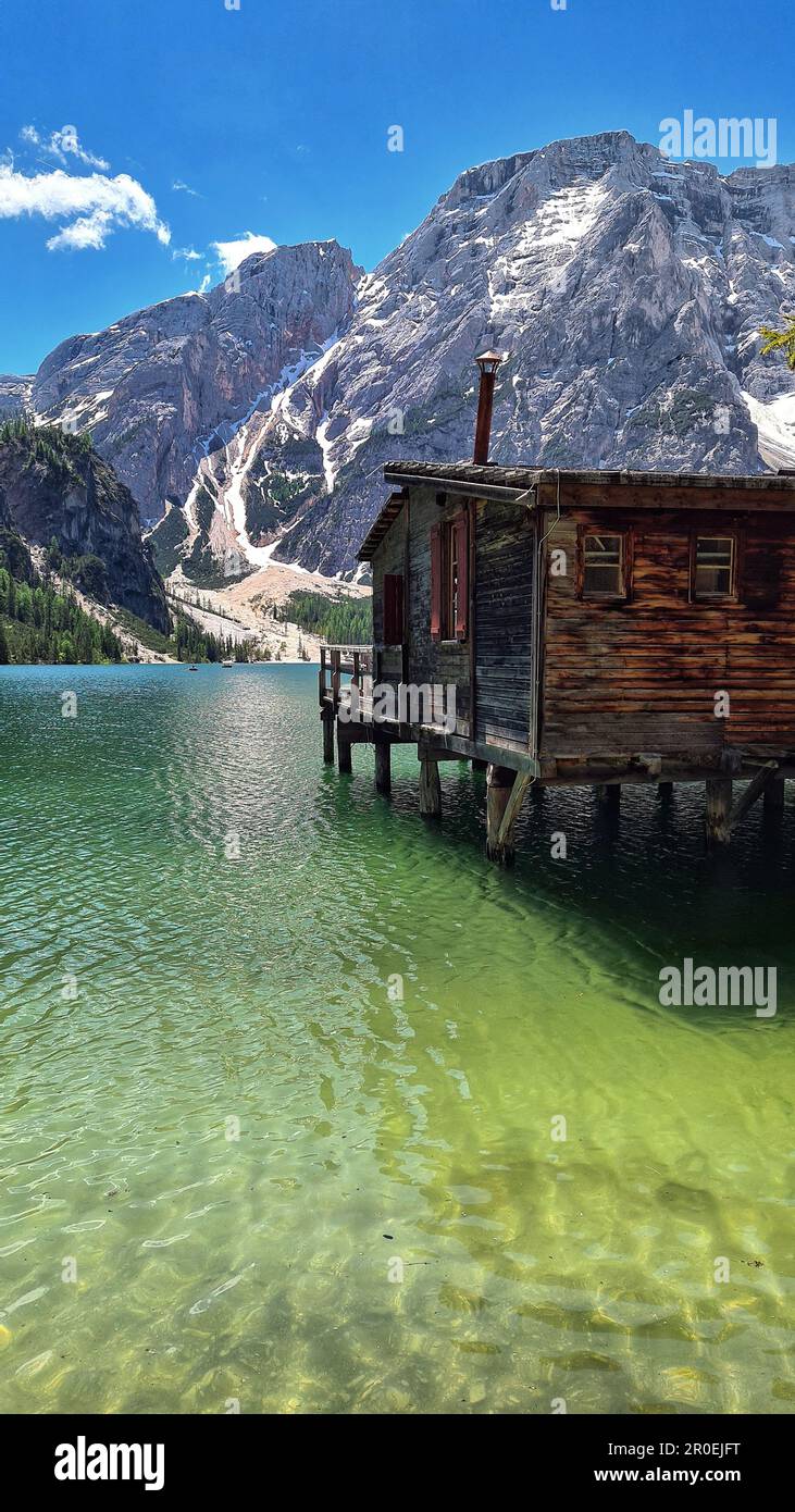 A rustic wooden cabin in the Braies tranquil lake, surrounded by a ...