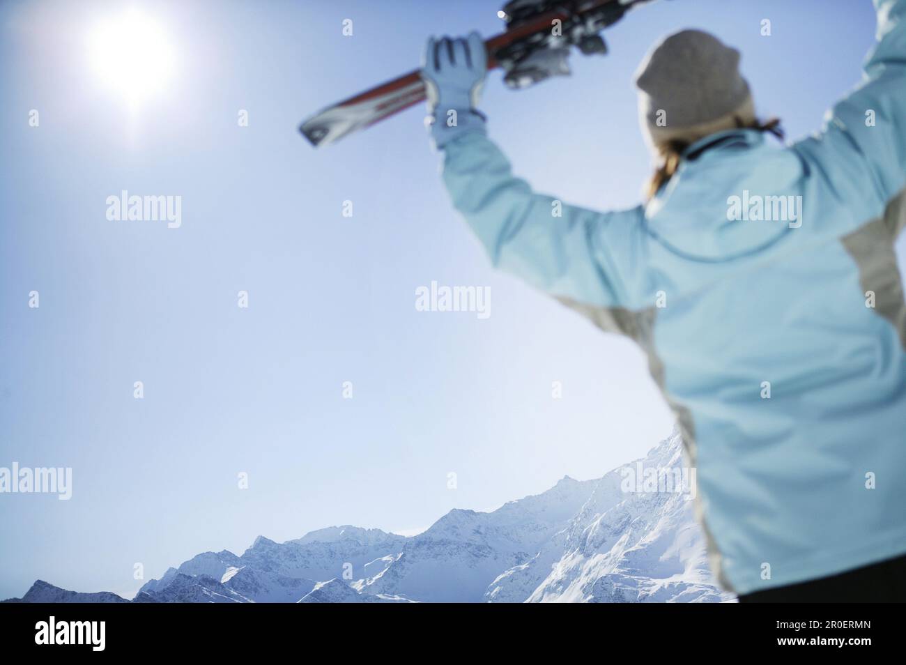 Woman holding skis up, mountains Hohe Mut and Gaisskogel in background, Kuhtai, Tyrol, Austria Stock Photo