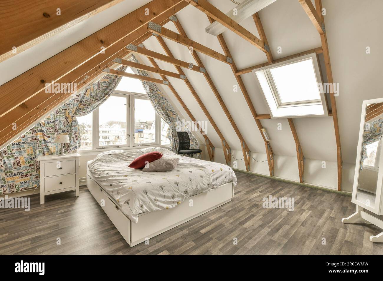 a bedroom with wood flooring and white bed in the corner of an attic ...