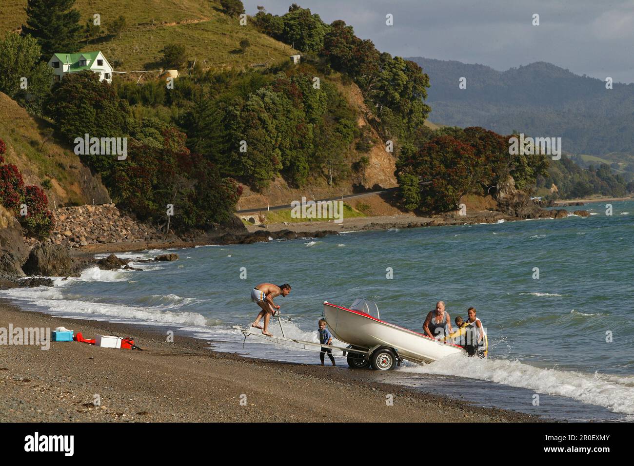 People on the beach launching a boat, Oamaru Bay, Coromandel Peninsula