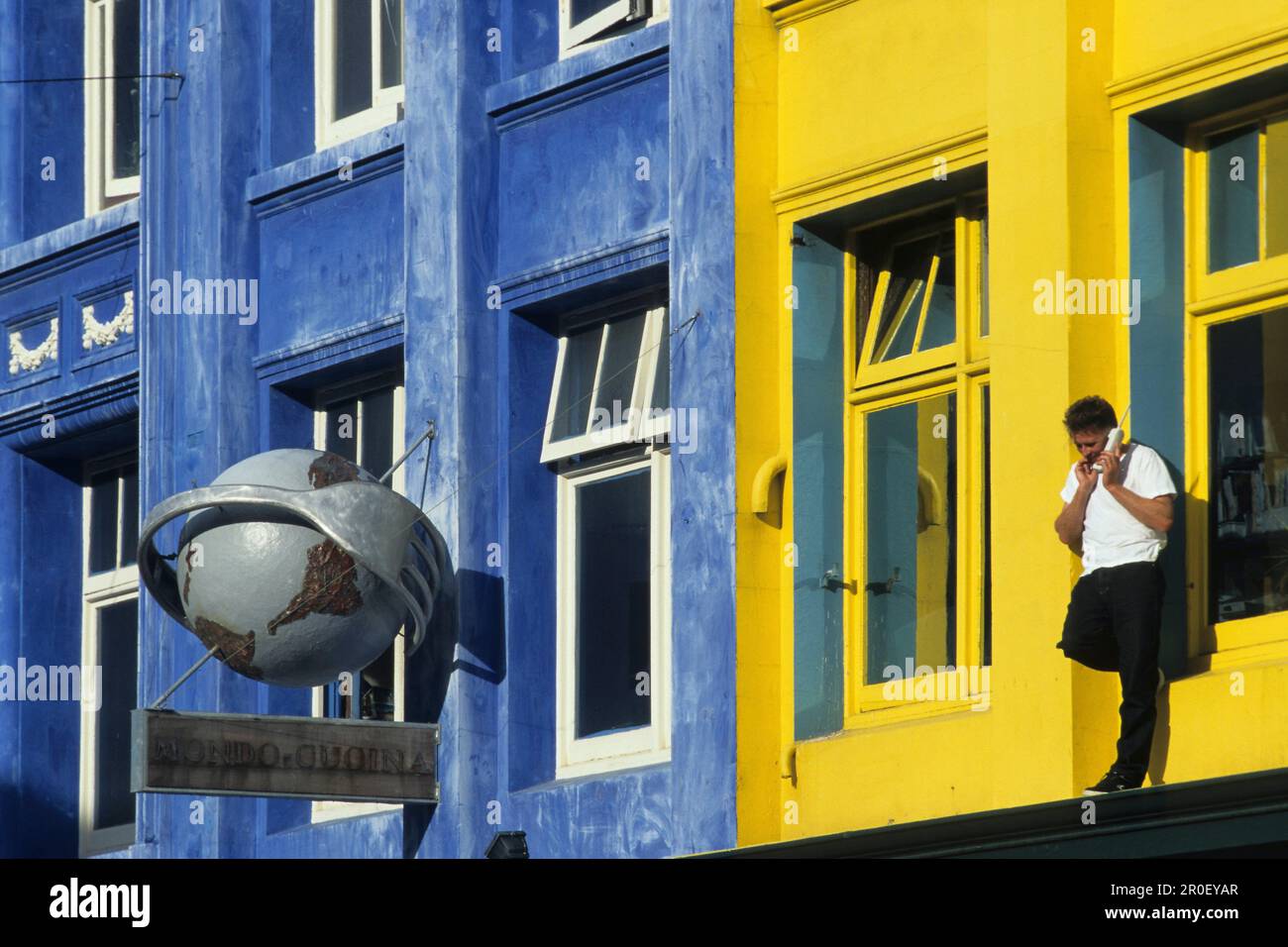 Telephoning outside coloured facade, Man with mobile phone outside building first floor, telefonieren mit Handy am Bunten Gebaudefassade, lifestyle Stock Photo