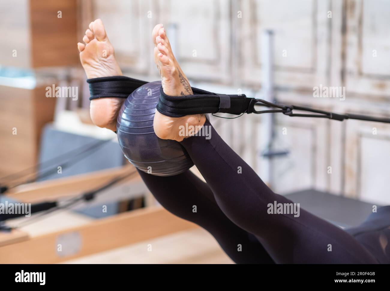 Pilates training for legs woman using fitness ball while exercising on
