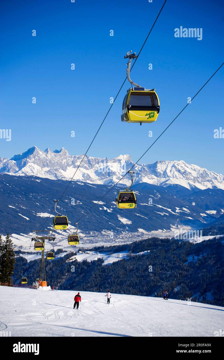 Cabin cable car and skiers on slope Dachstein Mountains at horizon ...