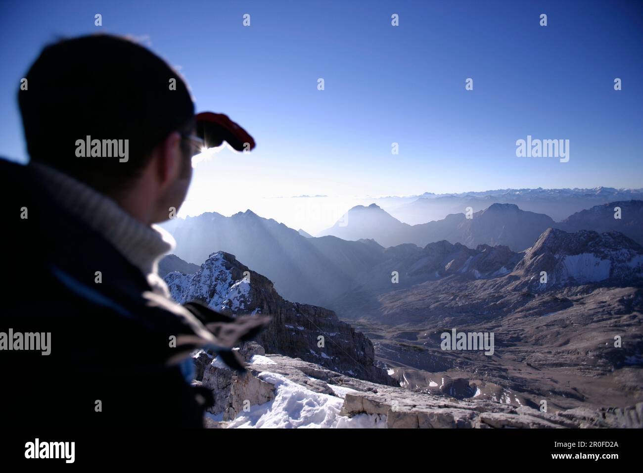 Man at the summit of the Zugspitze in the morning looking over Reintal, Bavaria, Germany Stock Photo