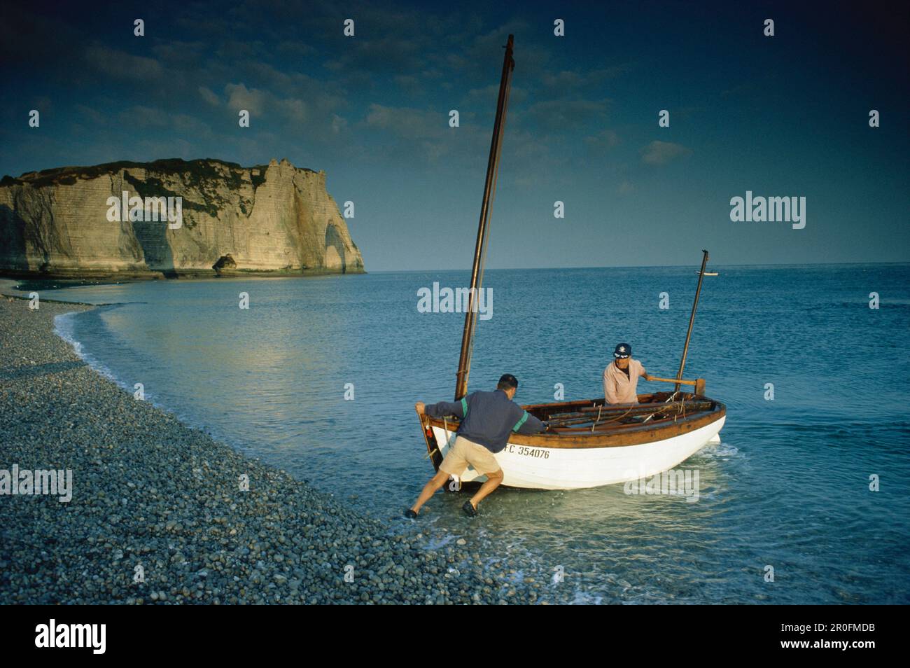 Two men pushing fishing boat into the water, Falaise, d´Aval, Etretat