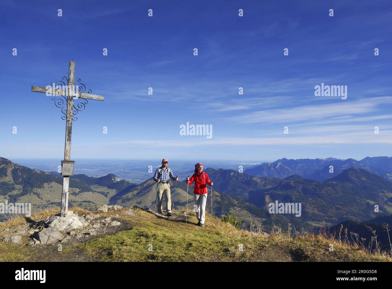 Couple reaching summit cross, Kleiner Traithen, Bavarian foothills, Bavaria, Germany Stock Photo