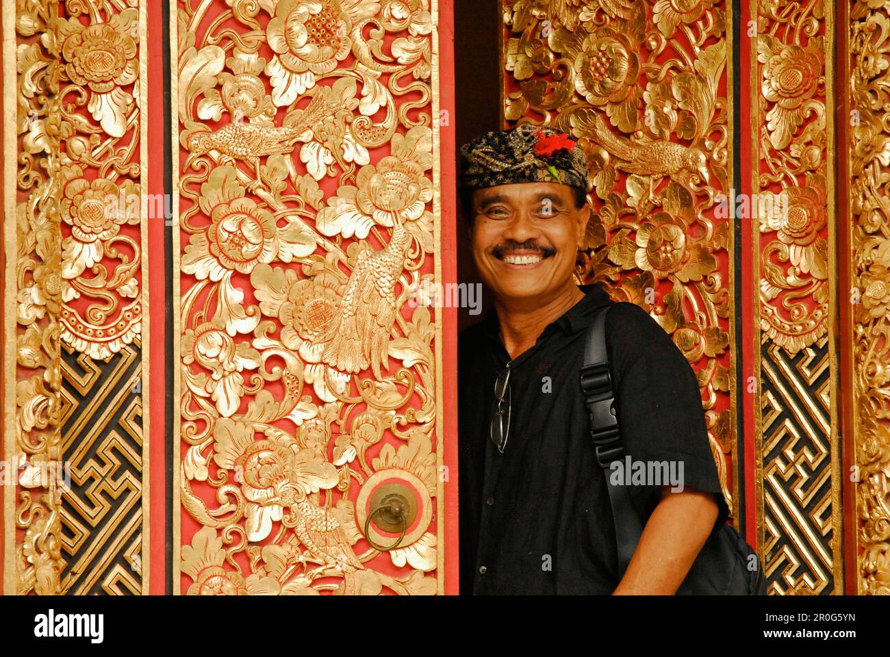 Laughing man at a carved door of his ARMA museum, Ubud, Bali, Indonesia, Asia Stock Photo