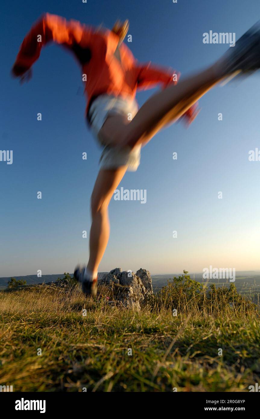 Jogger during a jump in the evening light, Franconian Switzerland, Bavaria, Germany, Europe Stock Photo