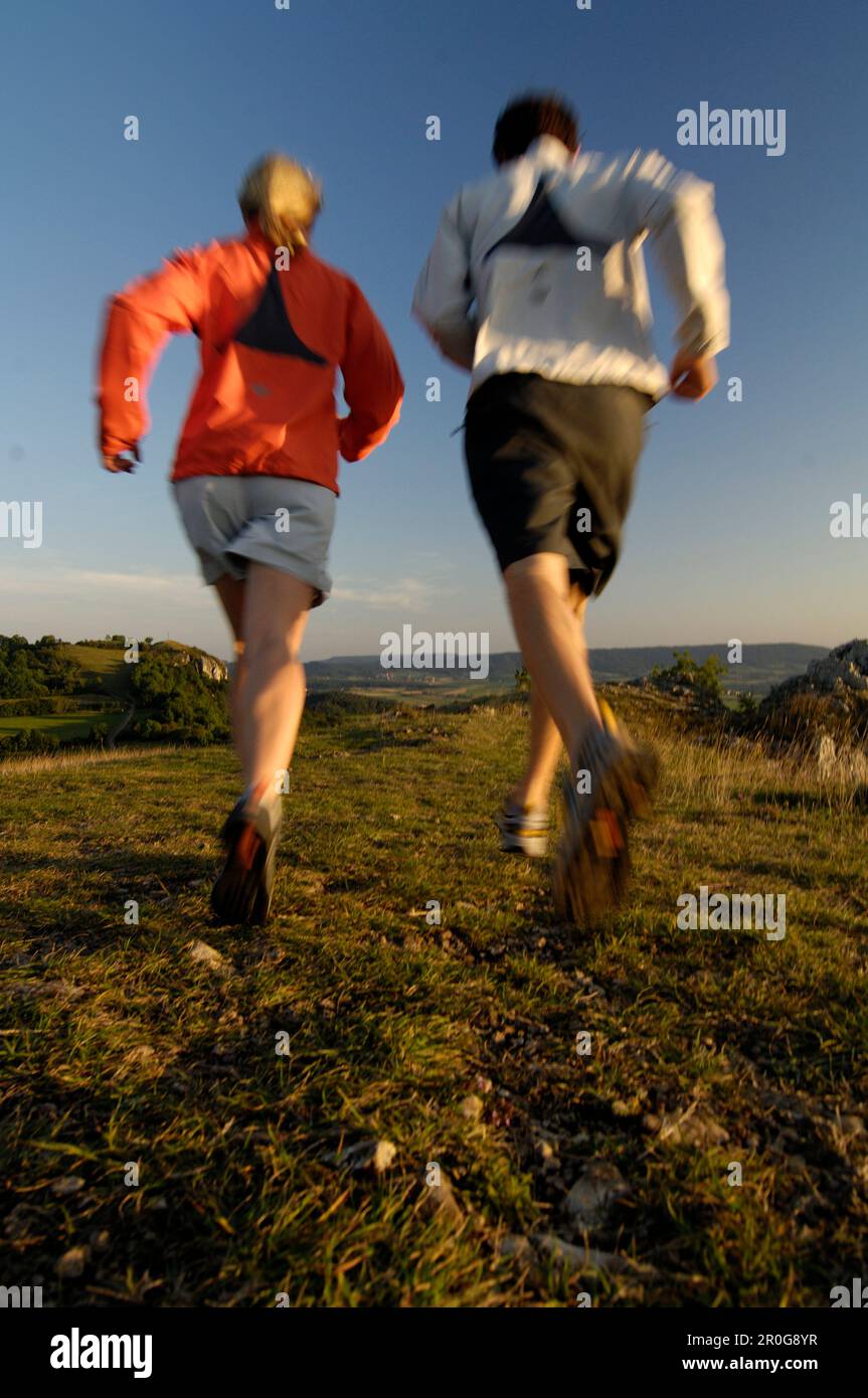 Couple jogging in the light of the evening sun, Franconian Switzerland, Bavaria, Germany, Europe Stock Photo