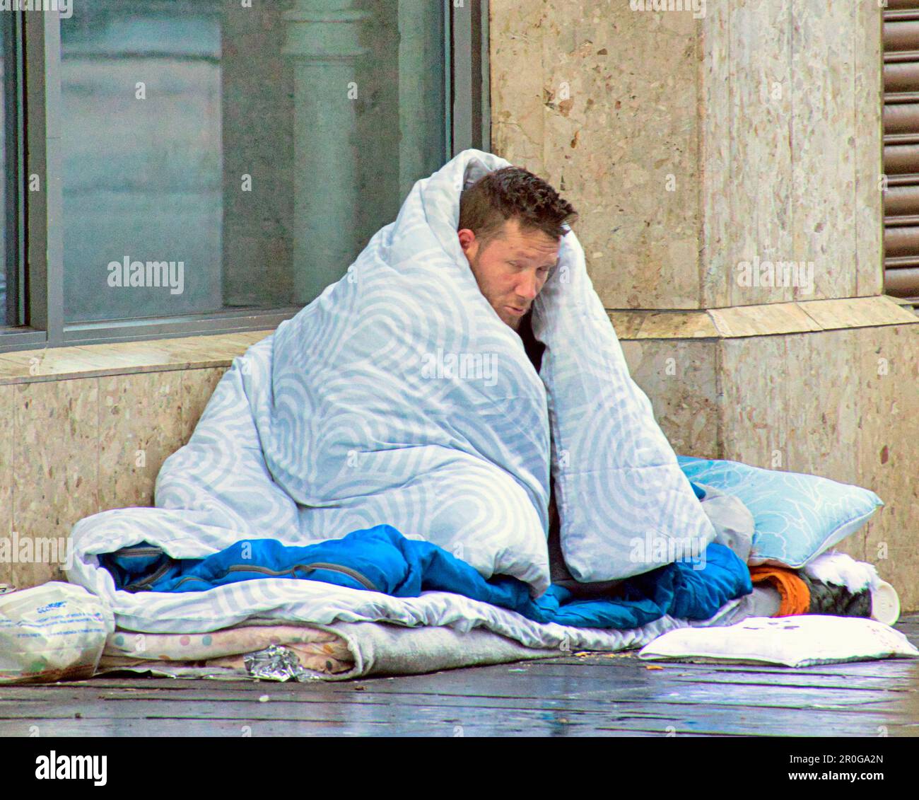 homeless man begging with duvet Stock Photo