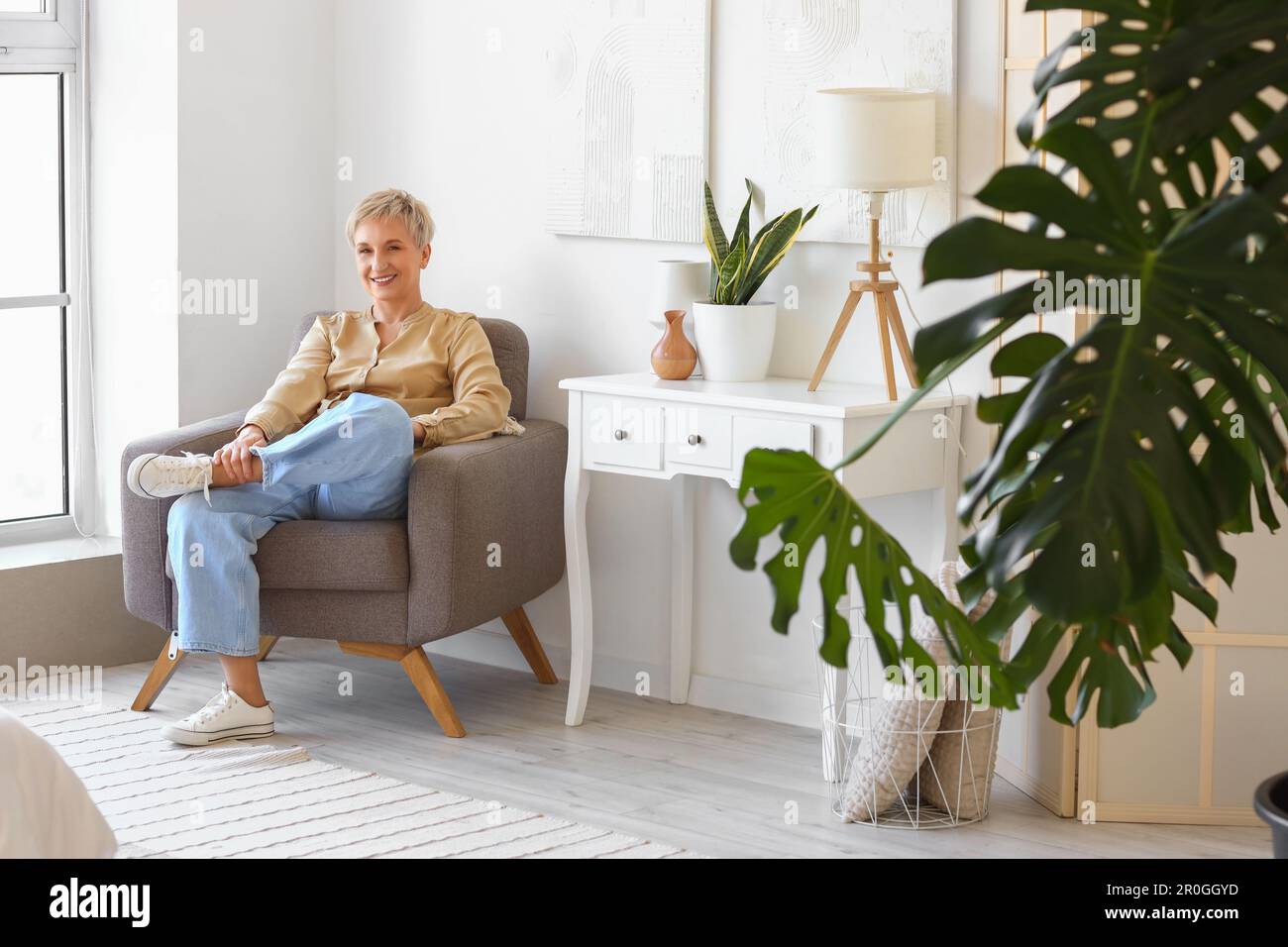 Mature woman sitting in armchair at home Stock Photo - Alamy