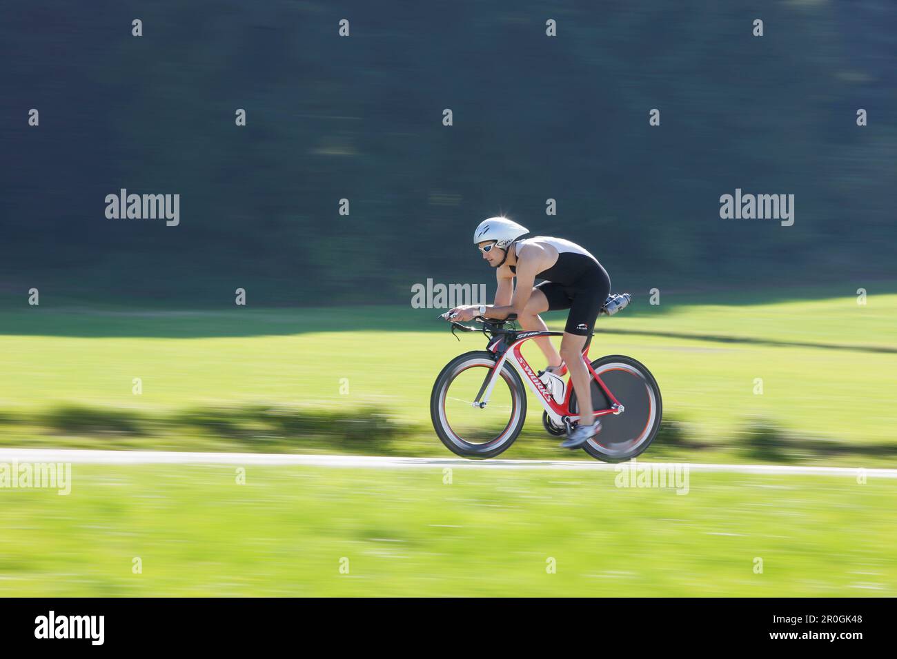 Male racing cyclist with disc wheel on road near Munsing, Upper Bavaria, Germany Stock Photo