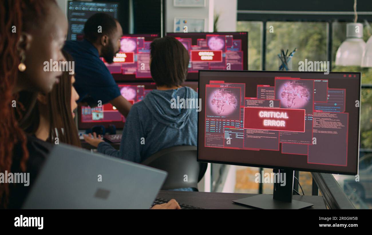 Team of system engineers having web server hacked, reading critical error on multiple monitors in office. Diverse software developers trying to solve hacking problem, firewall security. Stock Photo