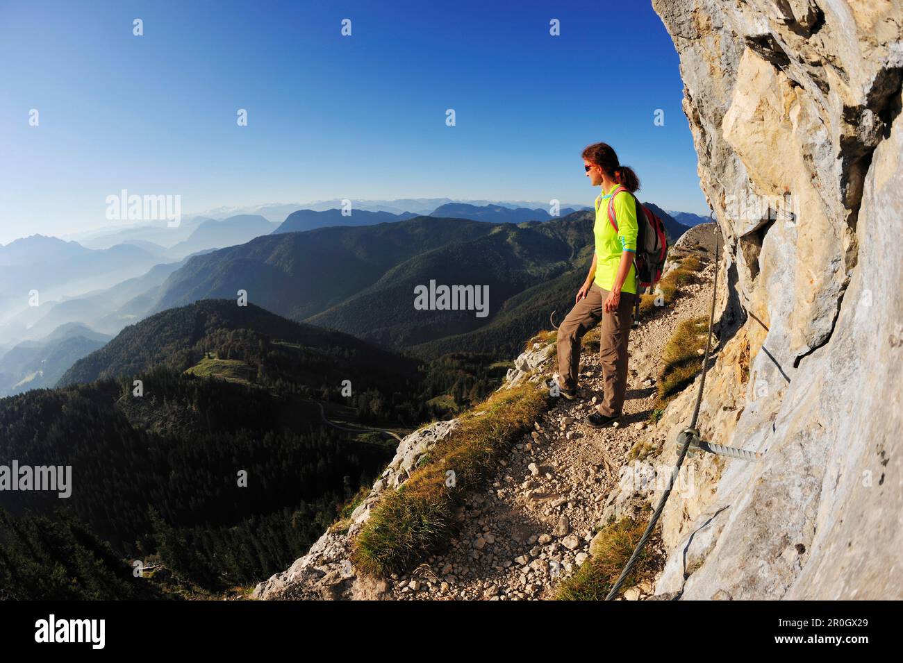 Woman walking on an exposed trail at a rockface, Brunnstein, Bavarian