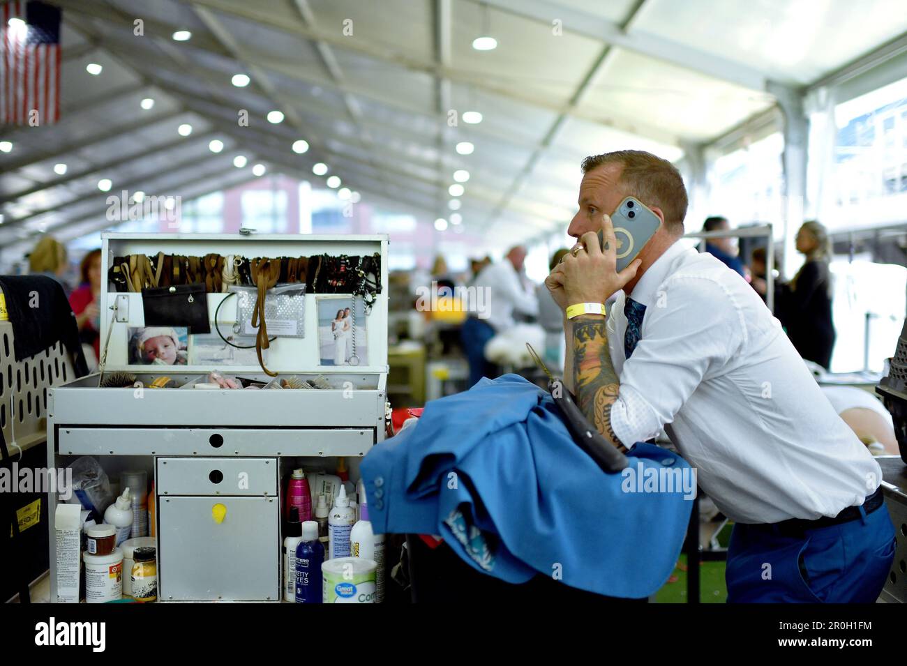 New York, USA. 08th May, 2023. Handler Jessy Sutton takes a call at his grooming station on day one of group judging at the 147th Westminster Kennel Club Dog Show at the USTA Billie Jean King National Tennis Center in Flushing Meadows-Corona Park, Queens, New York, Monday May 8, 2023. (Photo by Anthony Behar/Sipa USA) Credit: Sipa USA/Alamy Live News Stock Photo