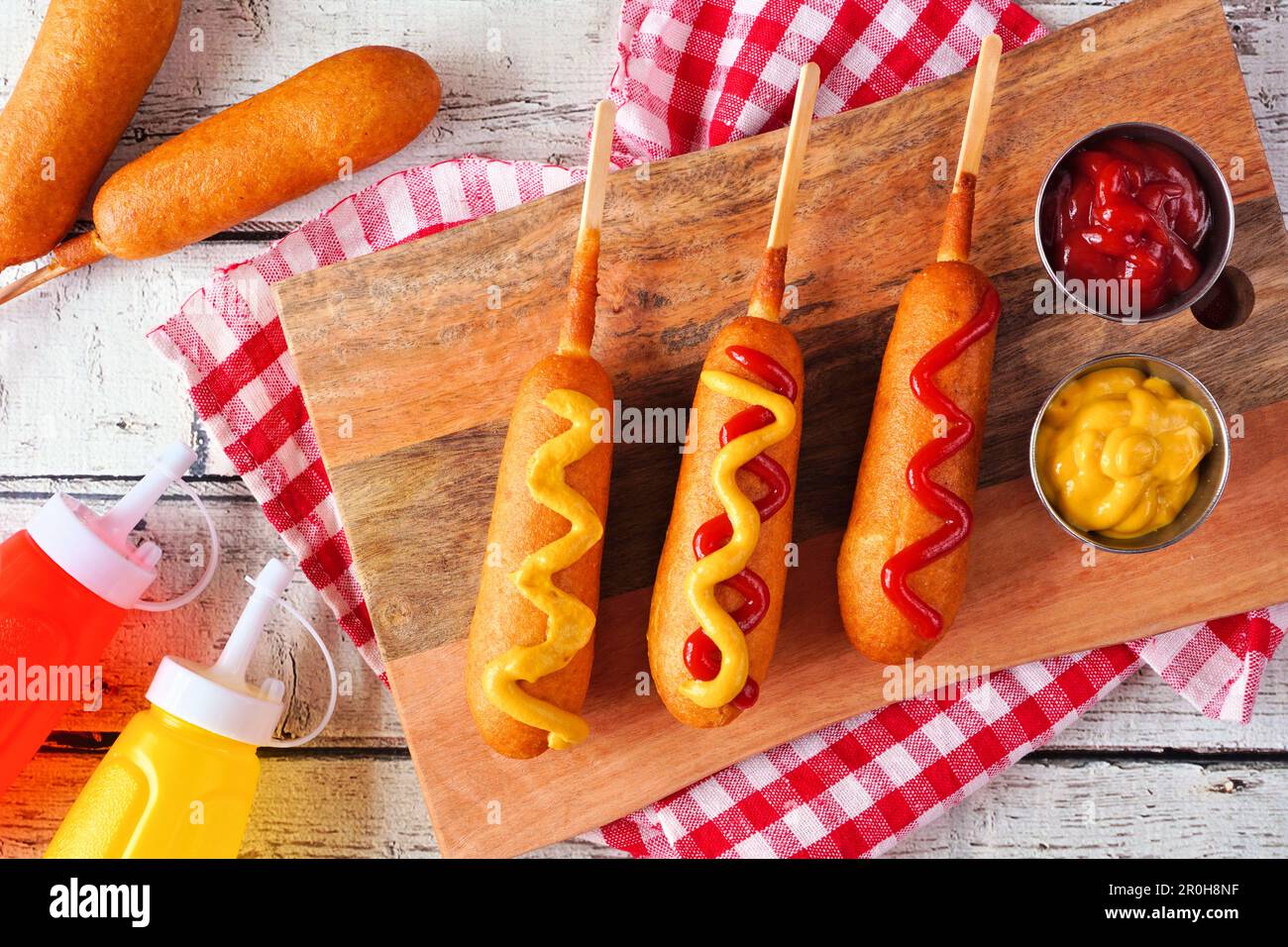 Corn dogs with mustard and ketchup. Top view table scene over a white