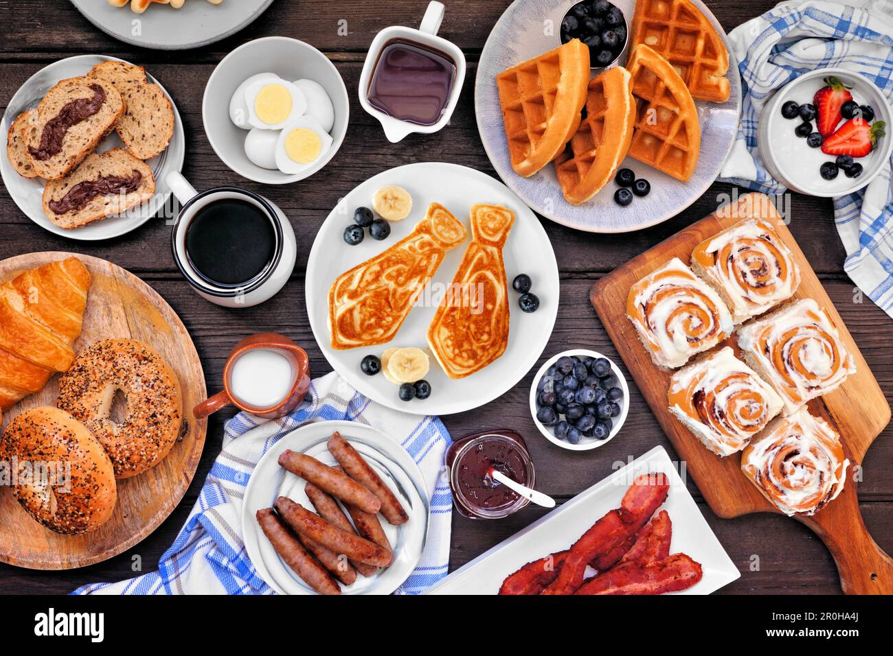Fathers Day brunch table scene. Above view on a dark wood background. Tie pancakes, mustache toast and a variety of dad themed food. Stock Photo