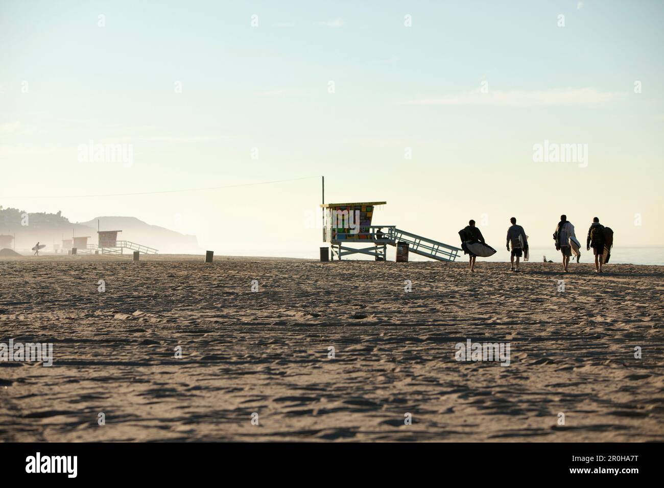 USA, California, Malibu, surfers walk across the sand towards the water at Zuma Beach Stock Photo