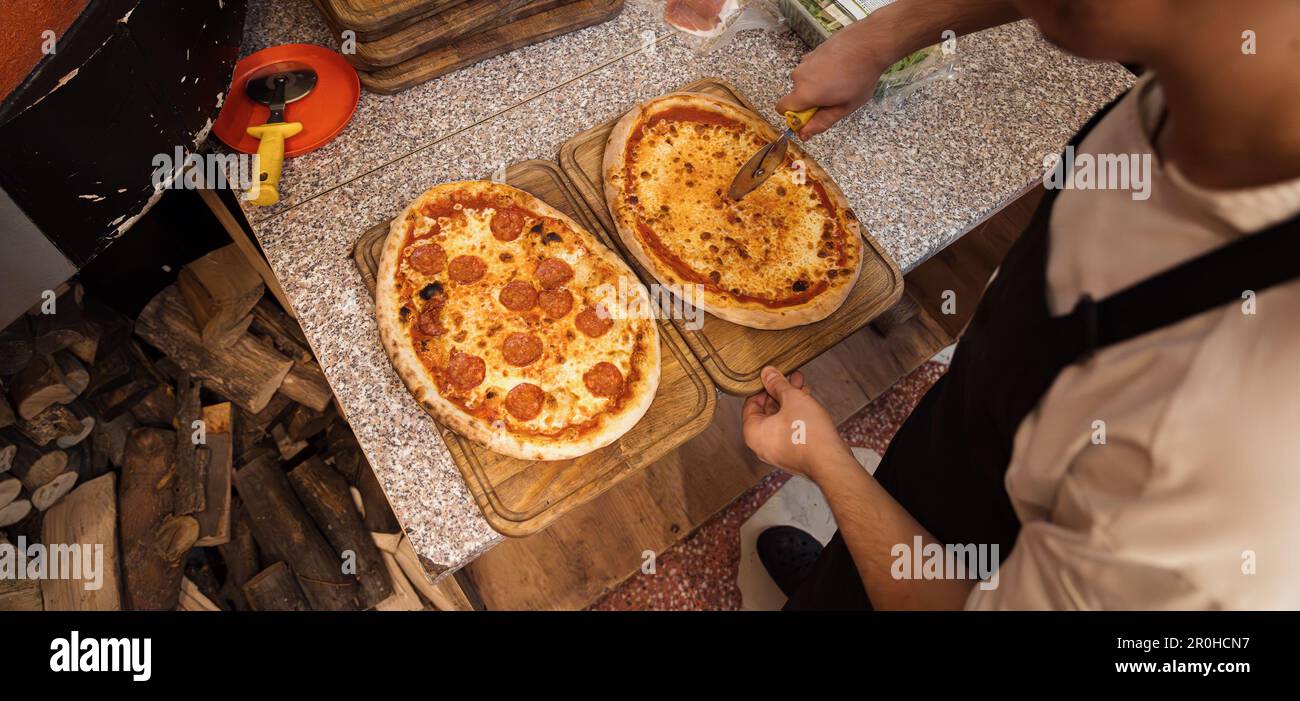 Close up of anonimous pizza chef slicing appetising pizza Stock Photo