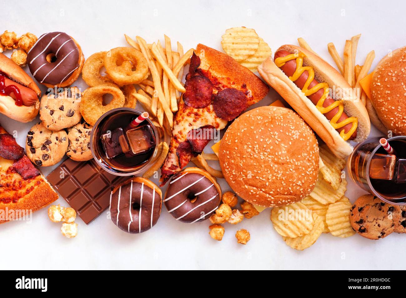 Junk food table scene scattered over a white marble background