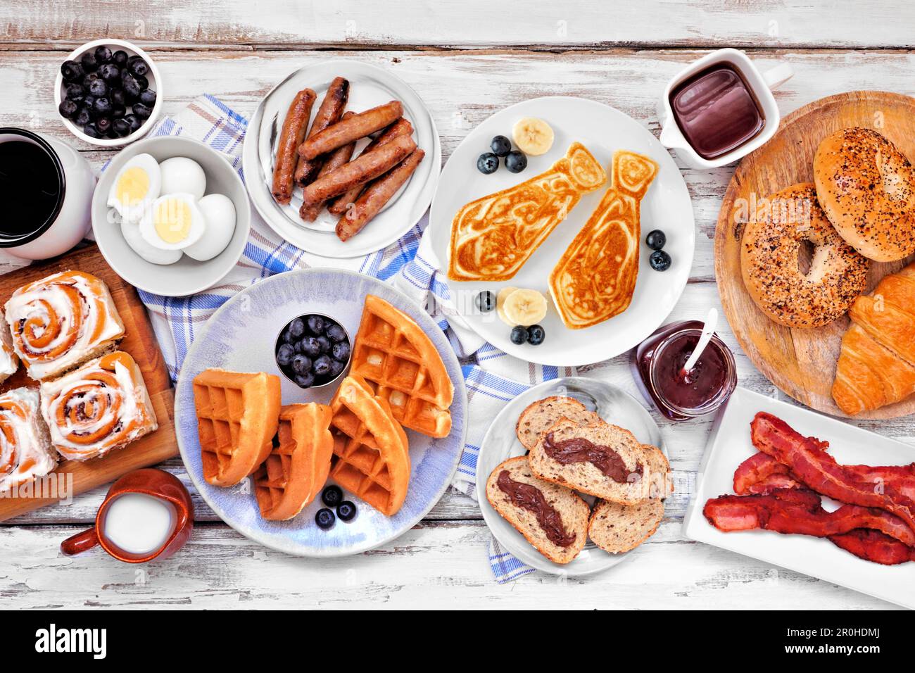 Fathers Day breakfast table scene. Overhead view on a white wood background. Tie pancakes, mustache toast and a selection of dad themed food. Stock Photo