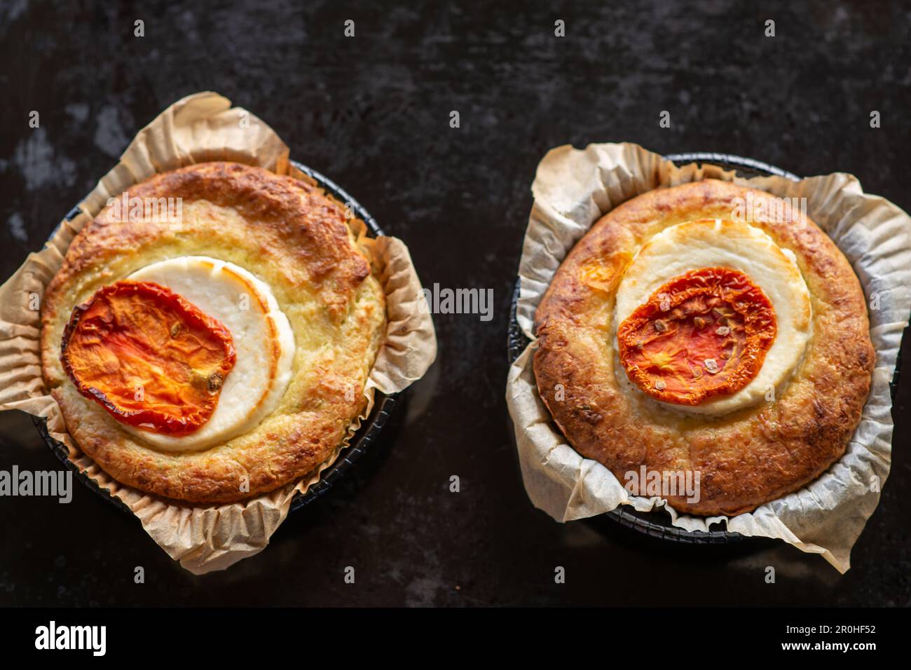 casserole with cheese and tomato. Two servings of round casseroles on a dark background. View from above. Stock Photo