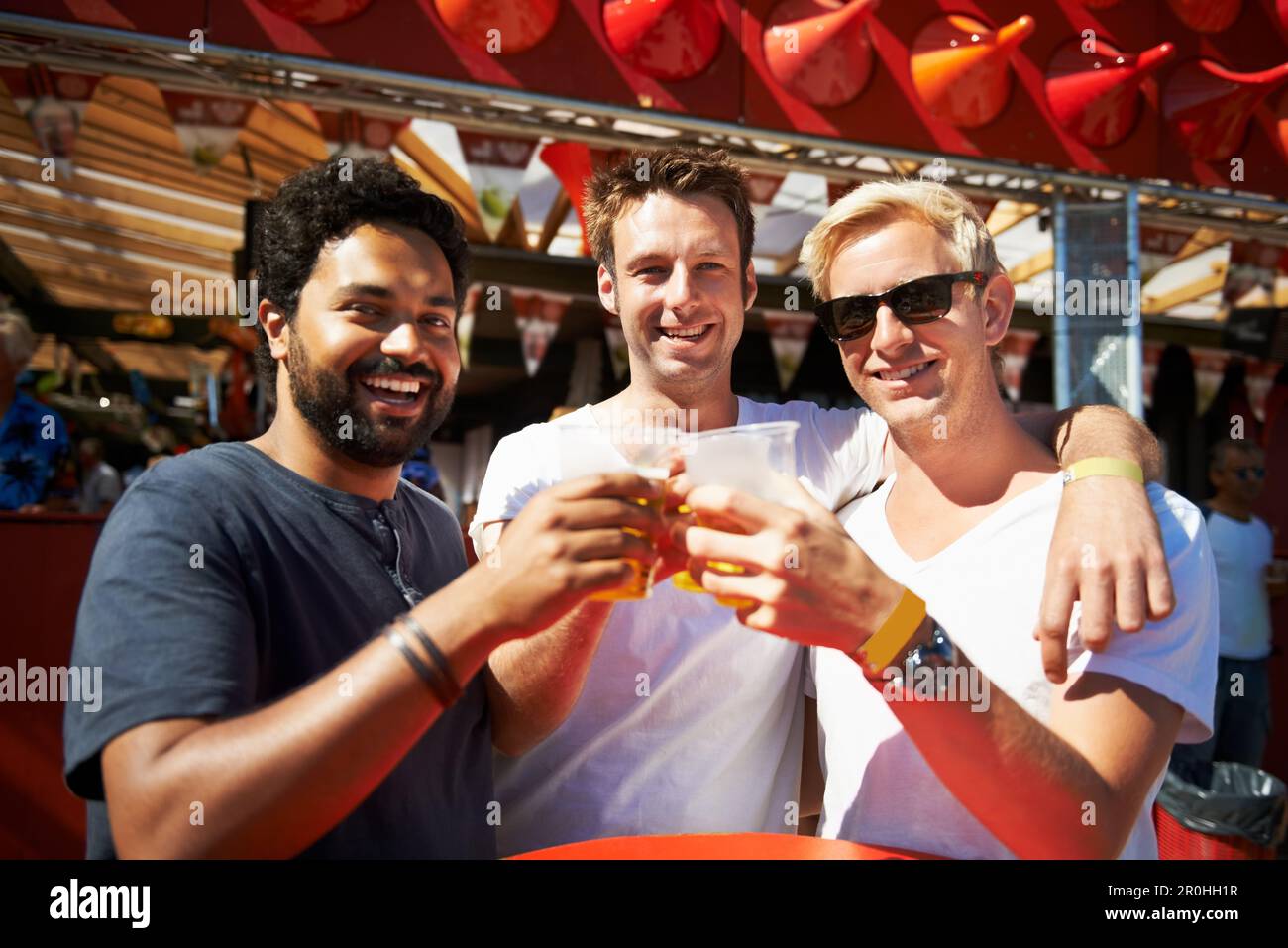 Getting started. Three young men toasting their beers at a music ...