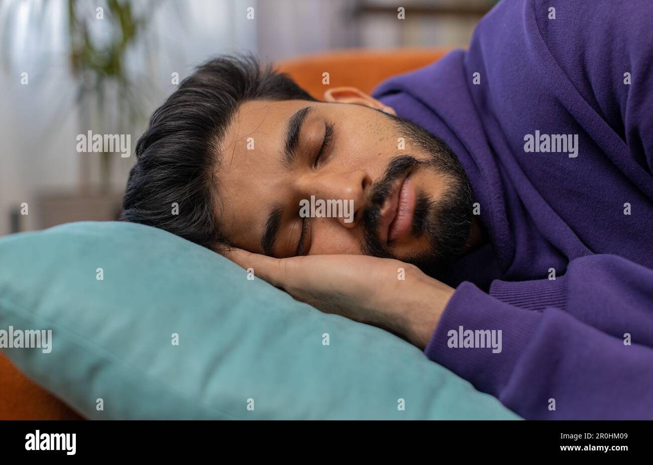 Tired indian man lying down in bed taking a rest. Carefree young