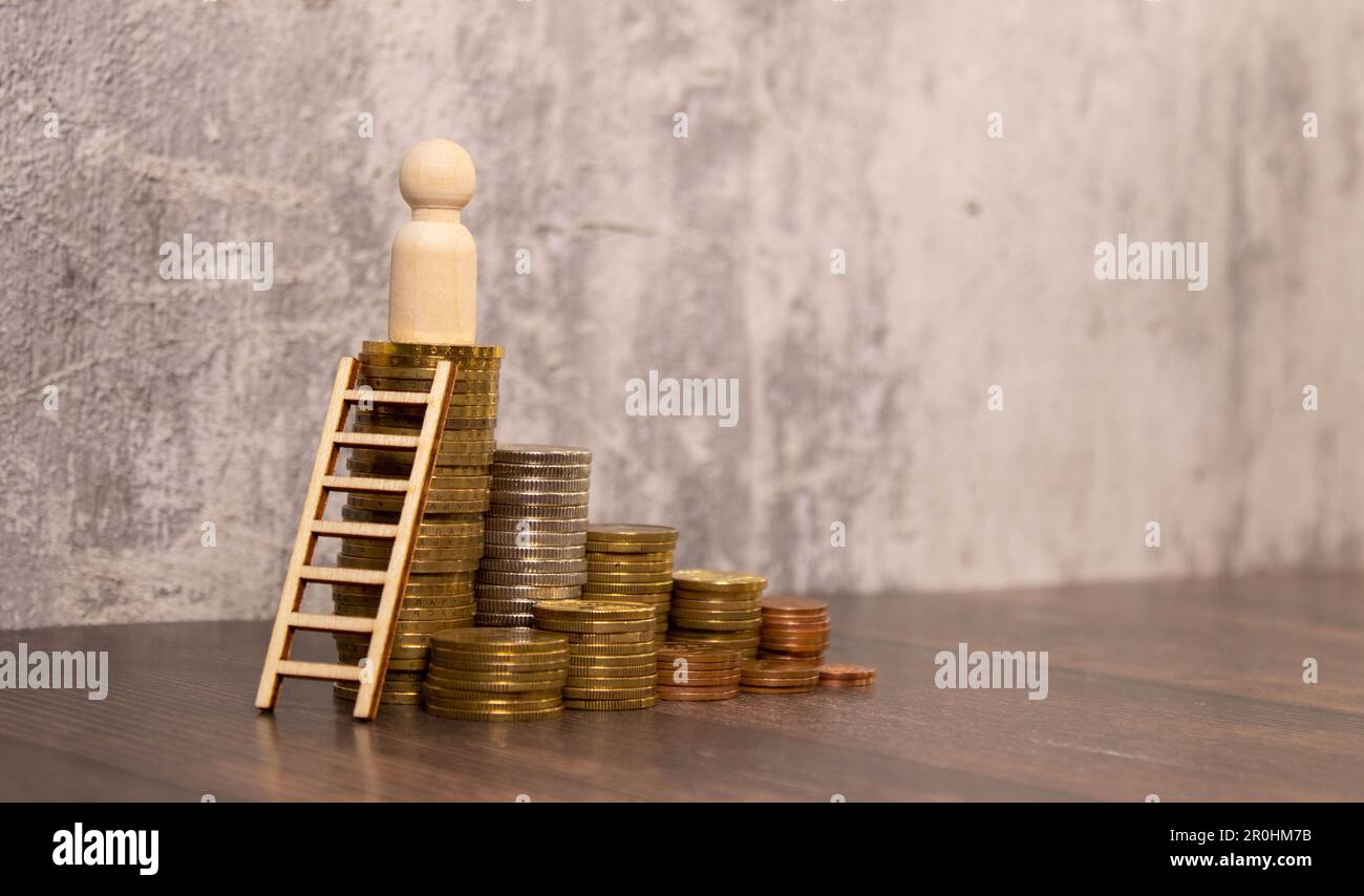 Miniature people: businessman figure raise your hand and holding a bag standing on stack of gold coin. Money ,investment and financial concepts. Stock Photo