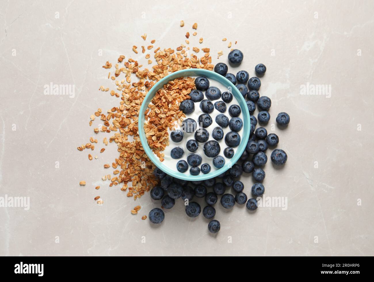 Bowl of yogurt with granola and blueberries on grey marble table, flat lay Stock Photo