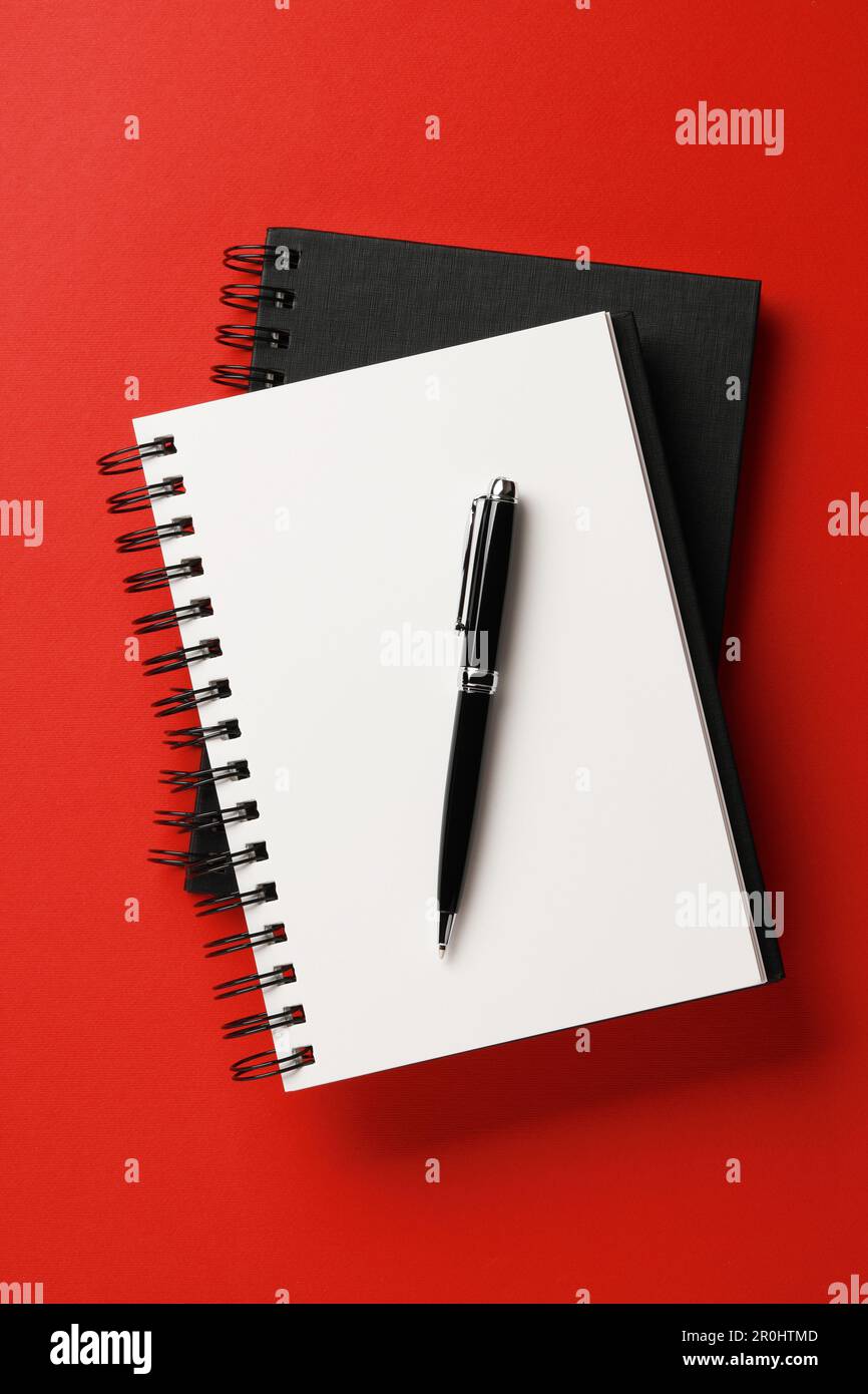 Notebooks and pen on red background, top view Stock Photo