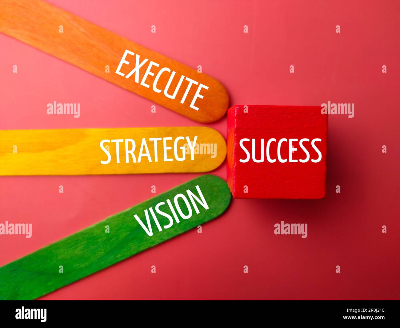 Wooden stick with the word SUCCESS EXECUTE STRATEGY VISION on a red background Stock Photo