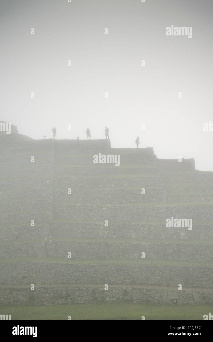 Group of tourists viewing the ruins of Machu Picchu surrounded by mist, Aguas Calientes, Peru, South America, 7 New Wonders of the World Stock Photo