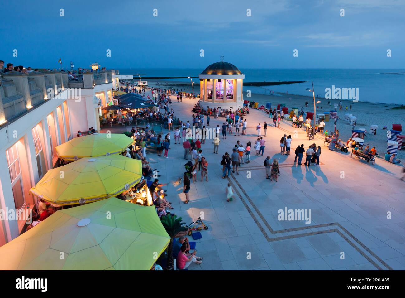 People sitting in a cafe on the beach promenade, Pavilion in the background, Borkum, Ostfriesland, Lower Saxony, Germany Stock Photo