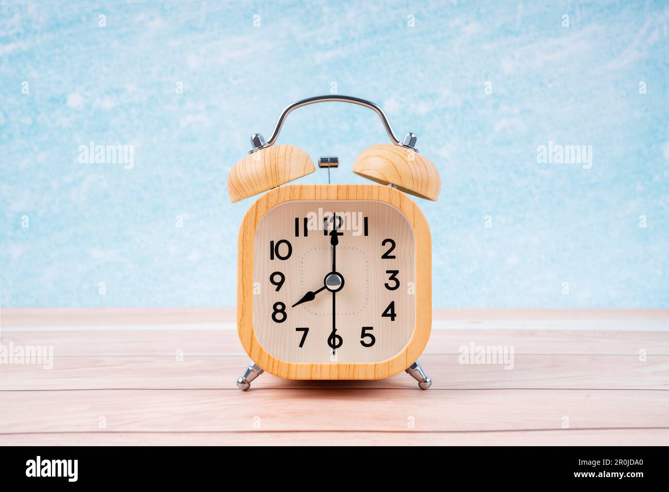 Wooden alarm clock on wooden floor with blue wall Stock Photo - Alamy