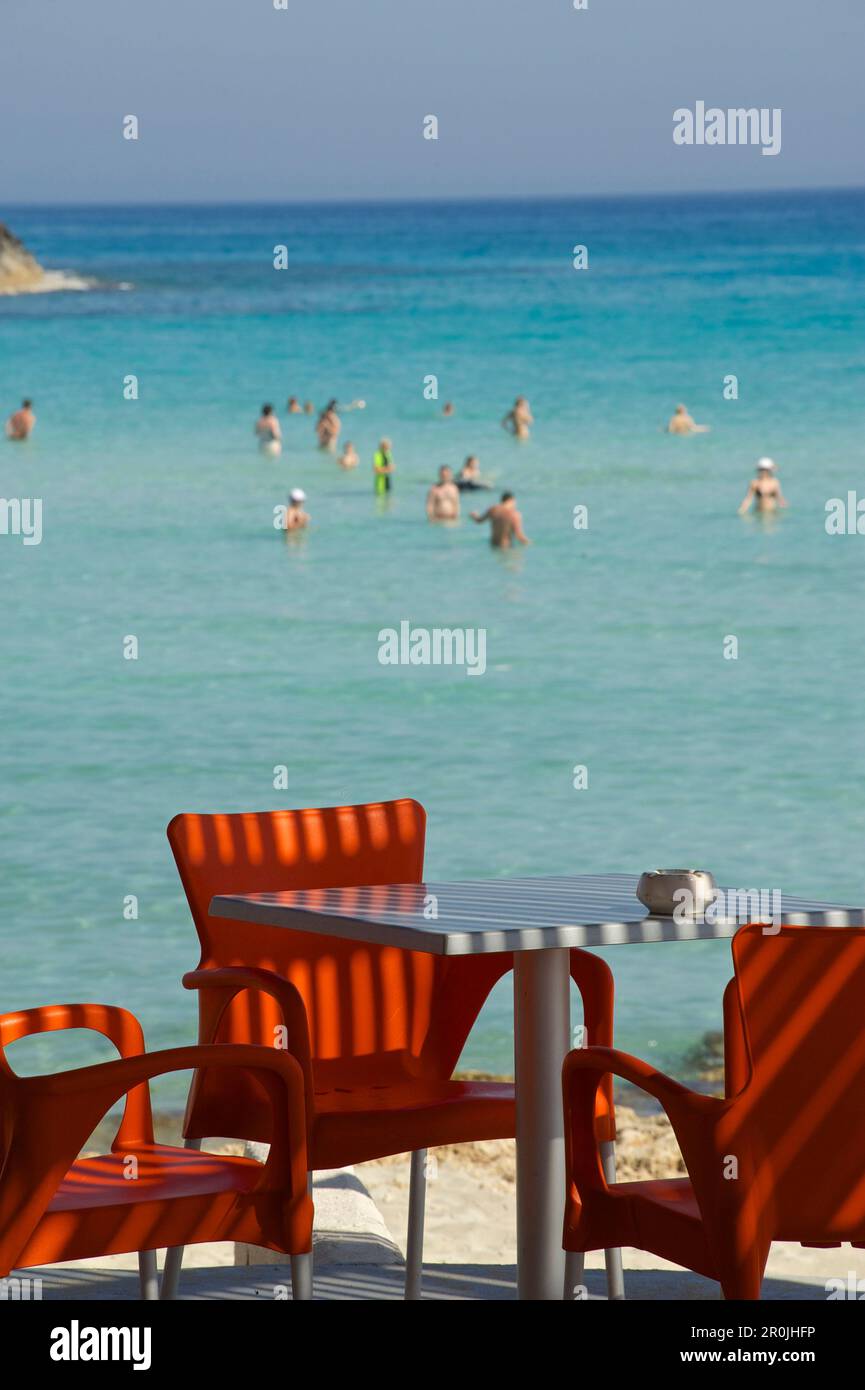 Red beach bar chairs and people in the water, Nissi Beach near Ayia