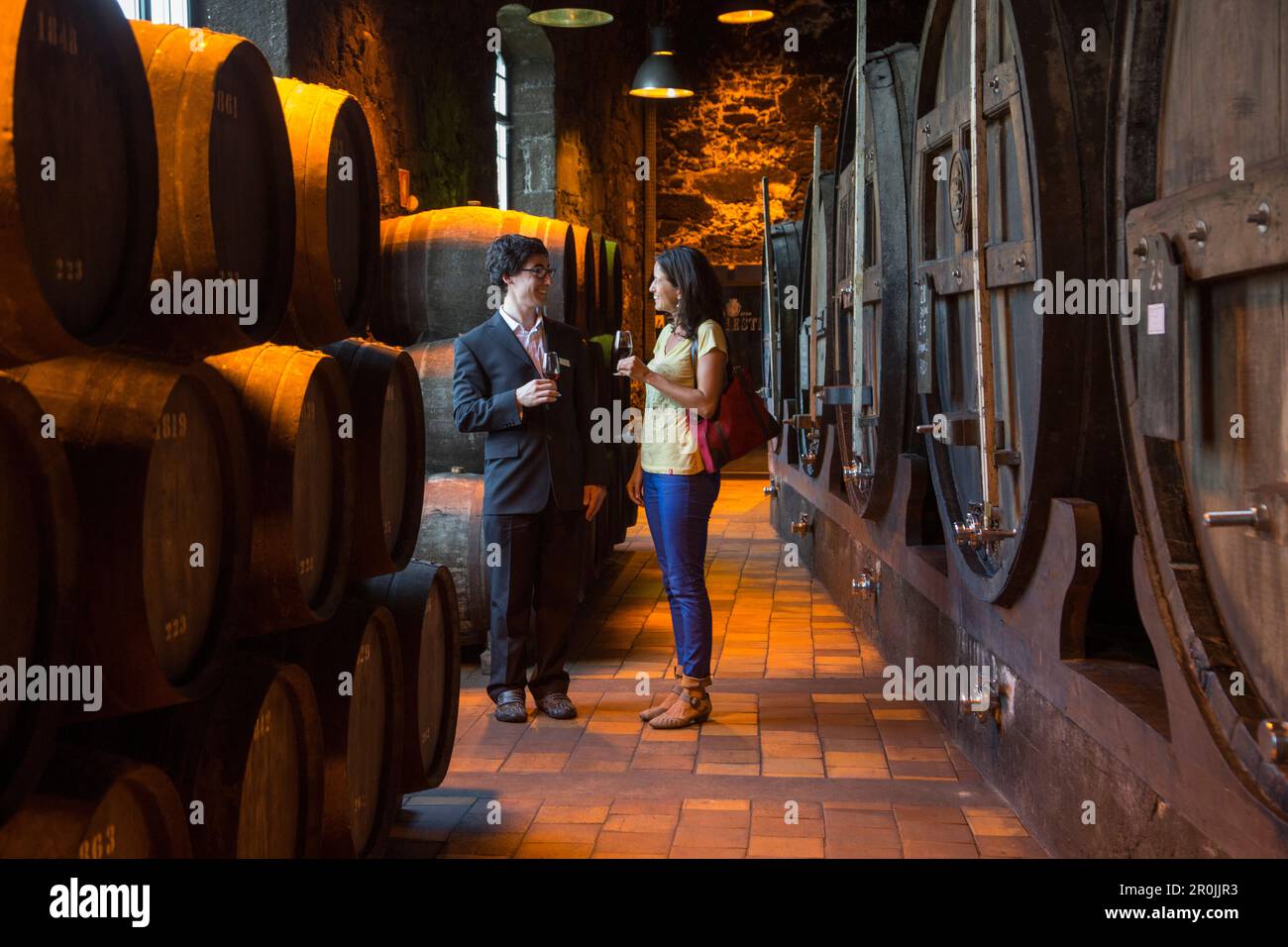 Man and woman enjoy port wine tasting in cellar of Burmester winery