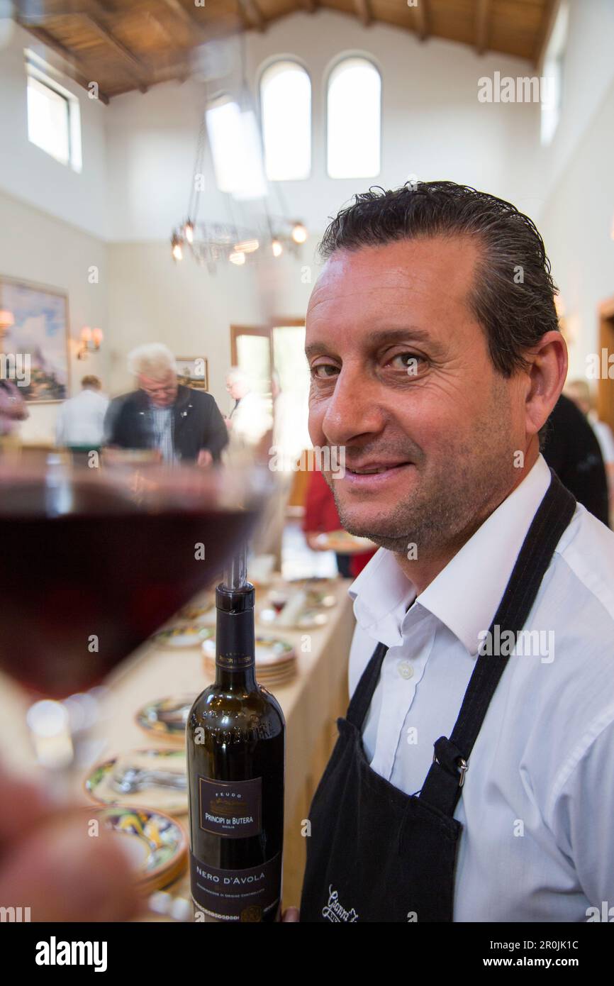 Waiter with wine bottle during winetasting at Feudo Principi di Butera winery, Deliella, near Butera, Sicily, Italy Stock Photo