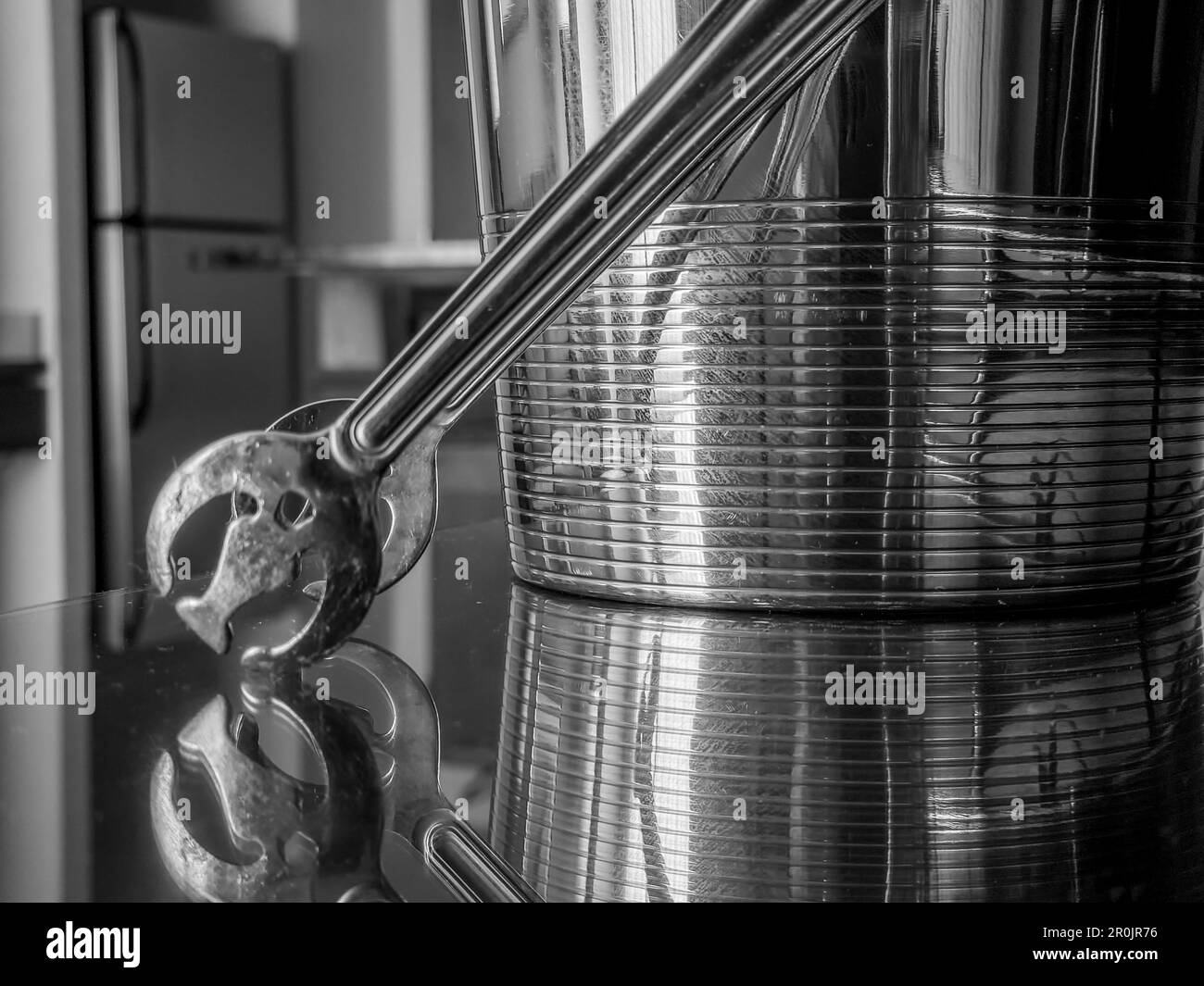 Stainless steel ice bucket reflecting off a mirror glass table in a